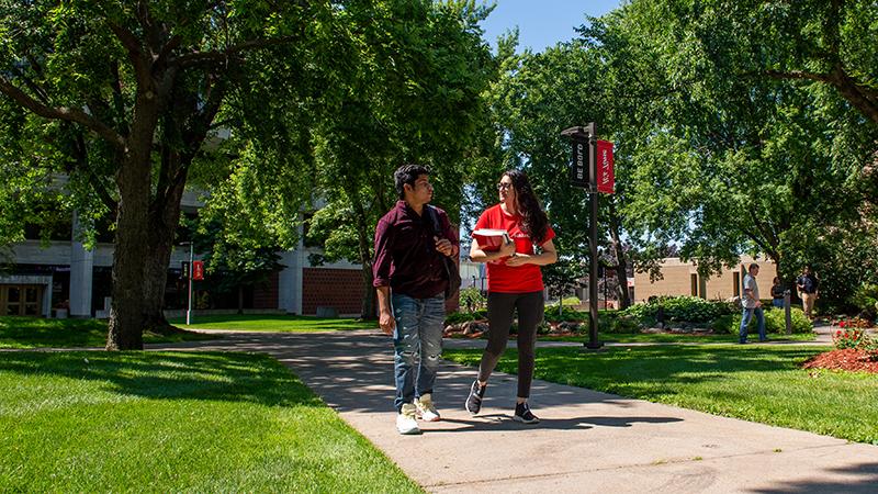 Two students walking on sidewalk.